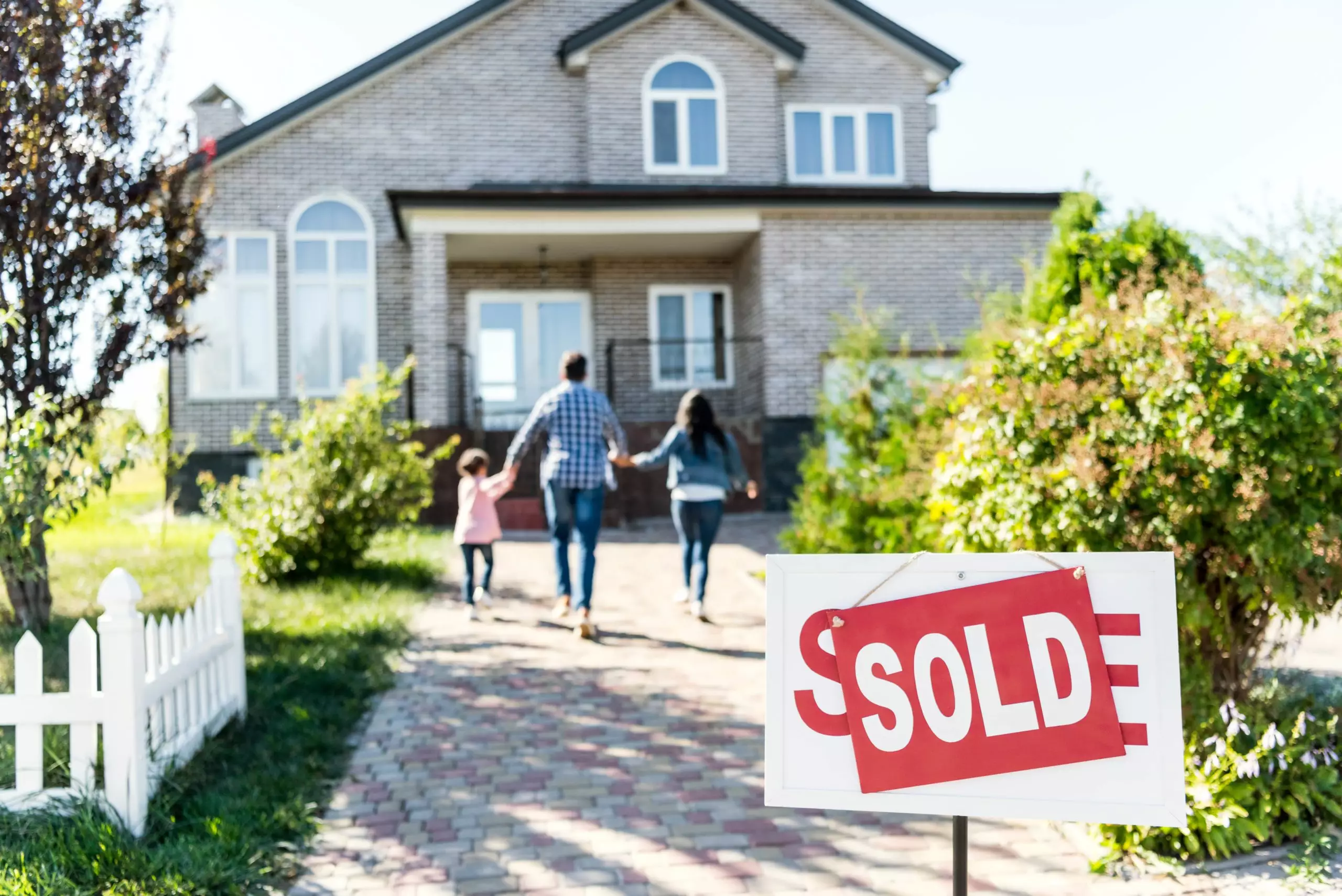 Family moving into new house with sold signboard on foreground