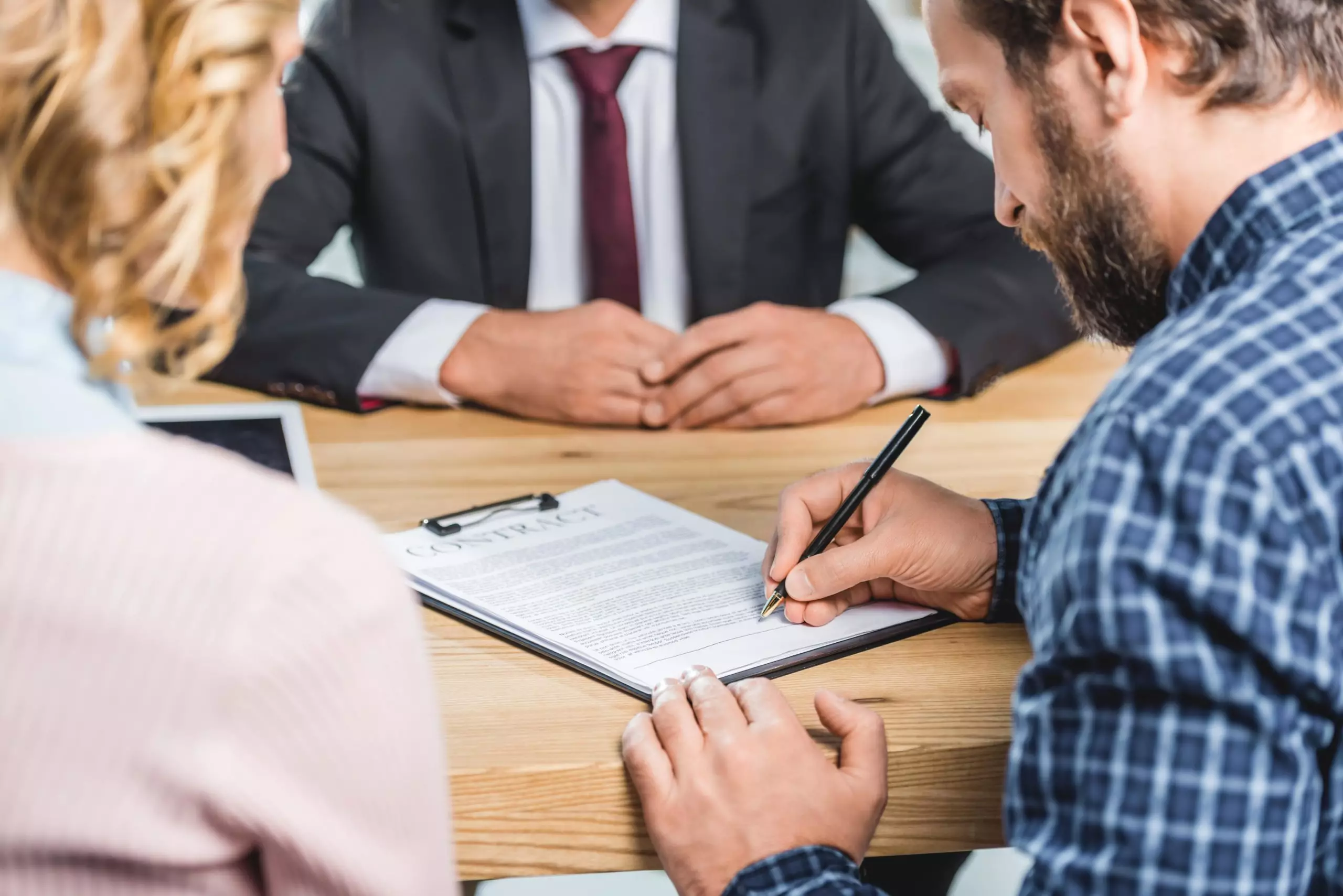 Selective focus of man signing contract at table in lawyers office